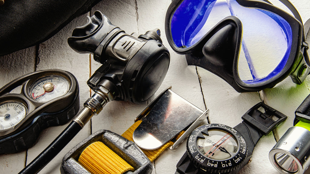 scuba diving equipment essentials showing a mask, regulator and a compass watch